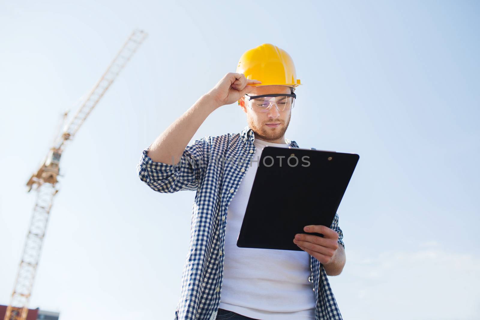 builder in hardhat with clipboard outdoors by dolgachov