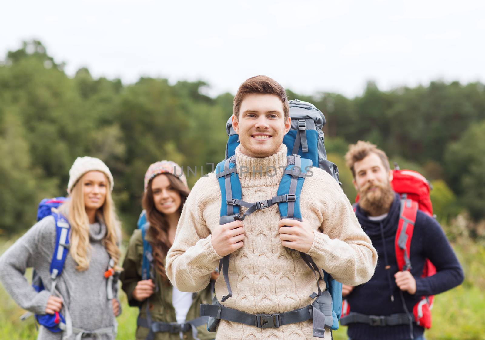 group of smiling friends with backpacks hiking by dolgachov