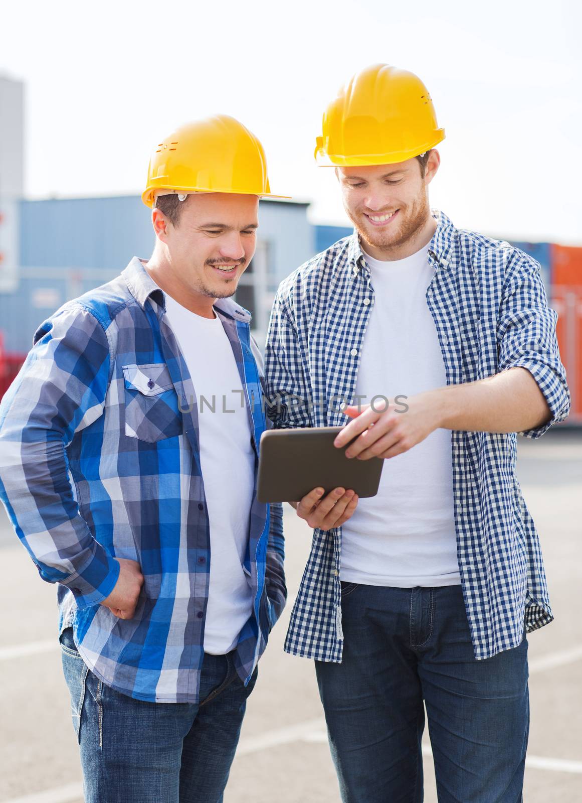 business, building, teamwork, technology and people concept - group of smiling builders in hardhats with tablet pc computer outdoors