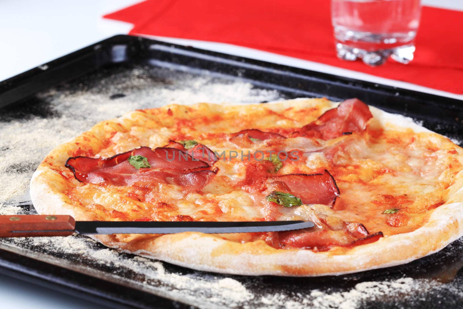 Fresh baked pizza prosciutto on a baking tin