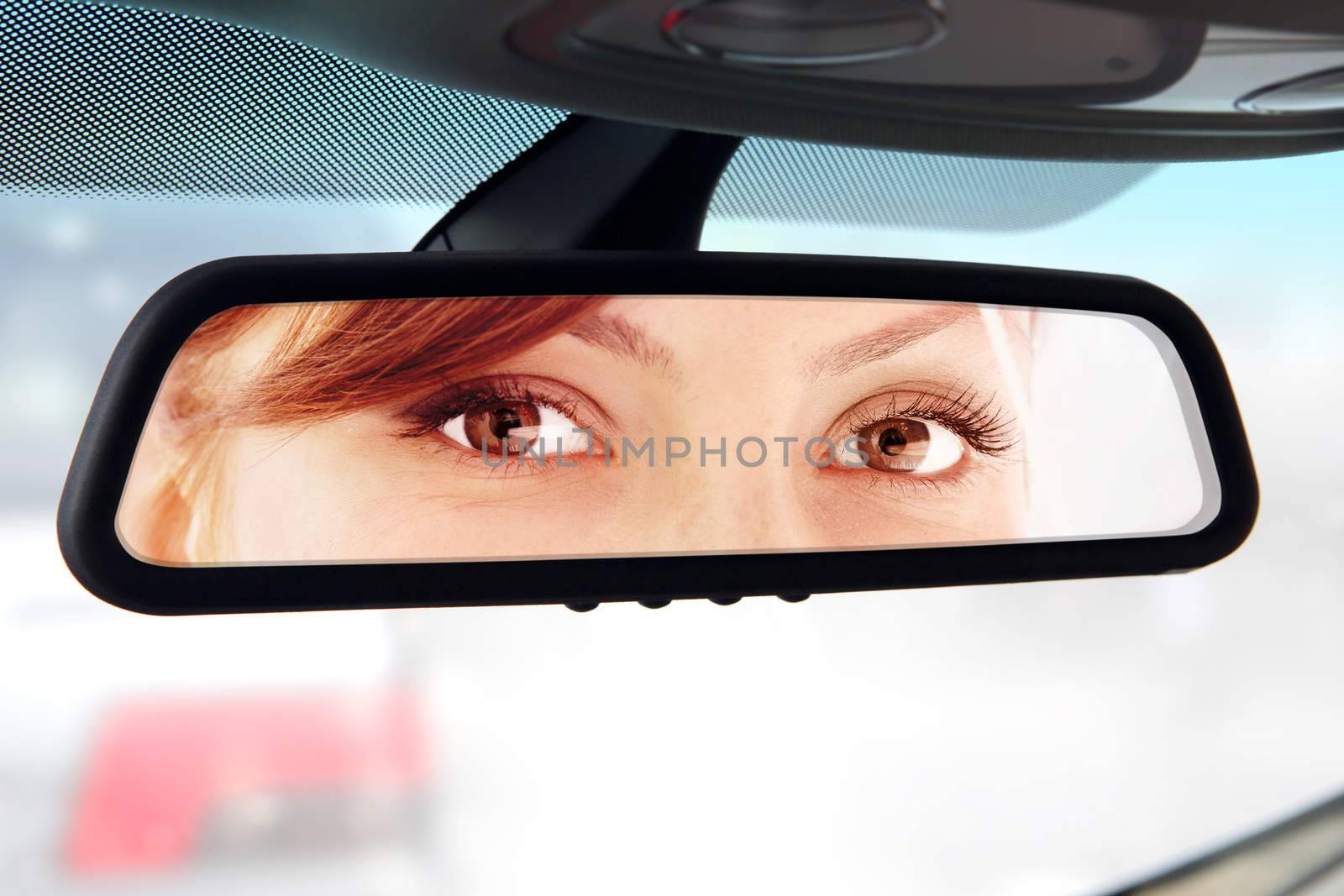woman looks to rear-view mirror by ssuaphoto