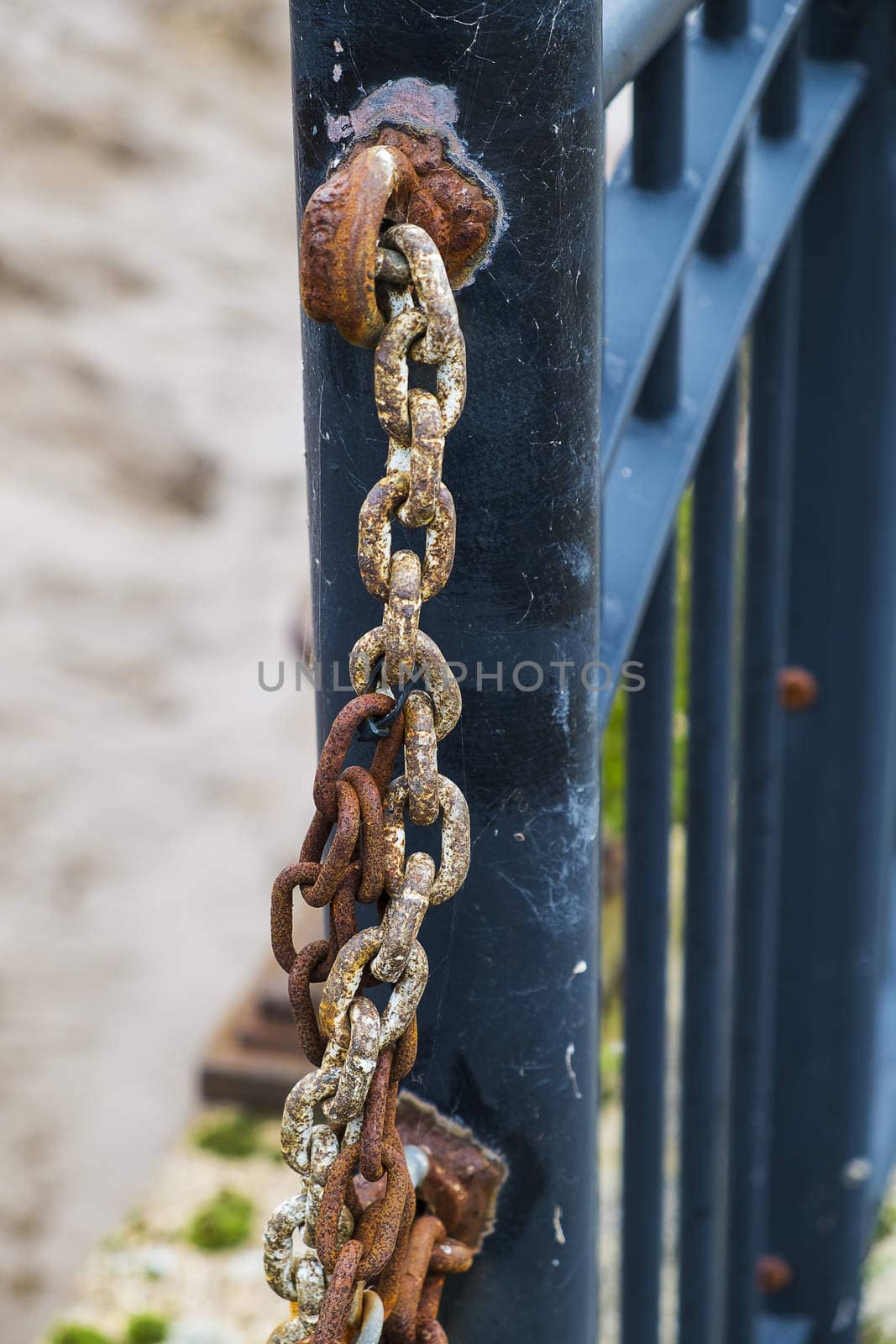 close up of rusted chain attached to metal fence