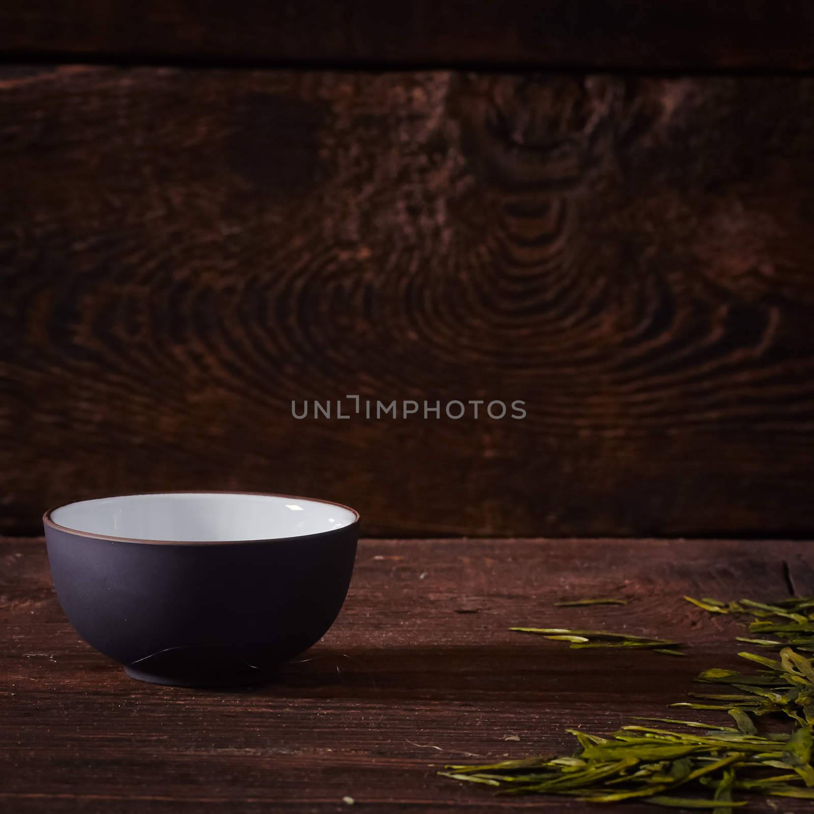 Ceramic tea cup, loose tea leaf on wood table