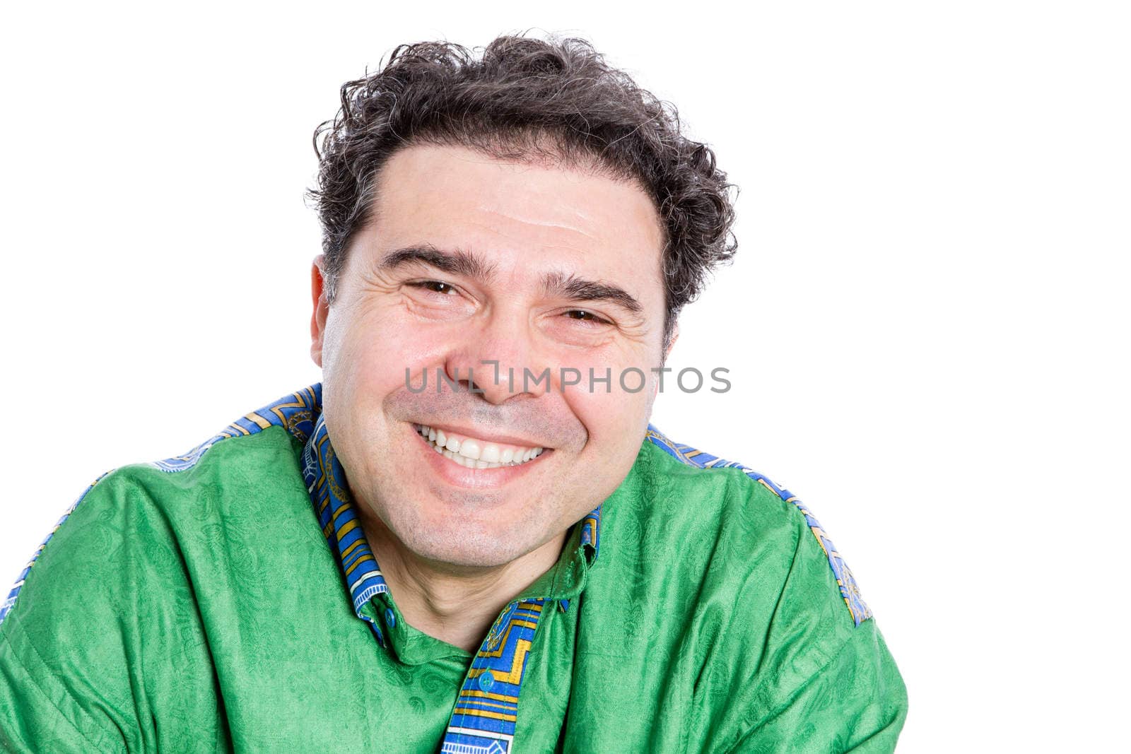 Happy handsome man with curly brown hair wearing a green afro shirt looking at the camera with a wide beaming smile of pleasure and delight, isolated on white