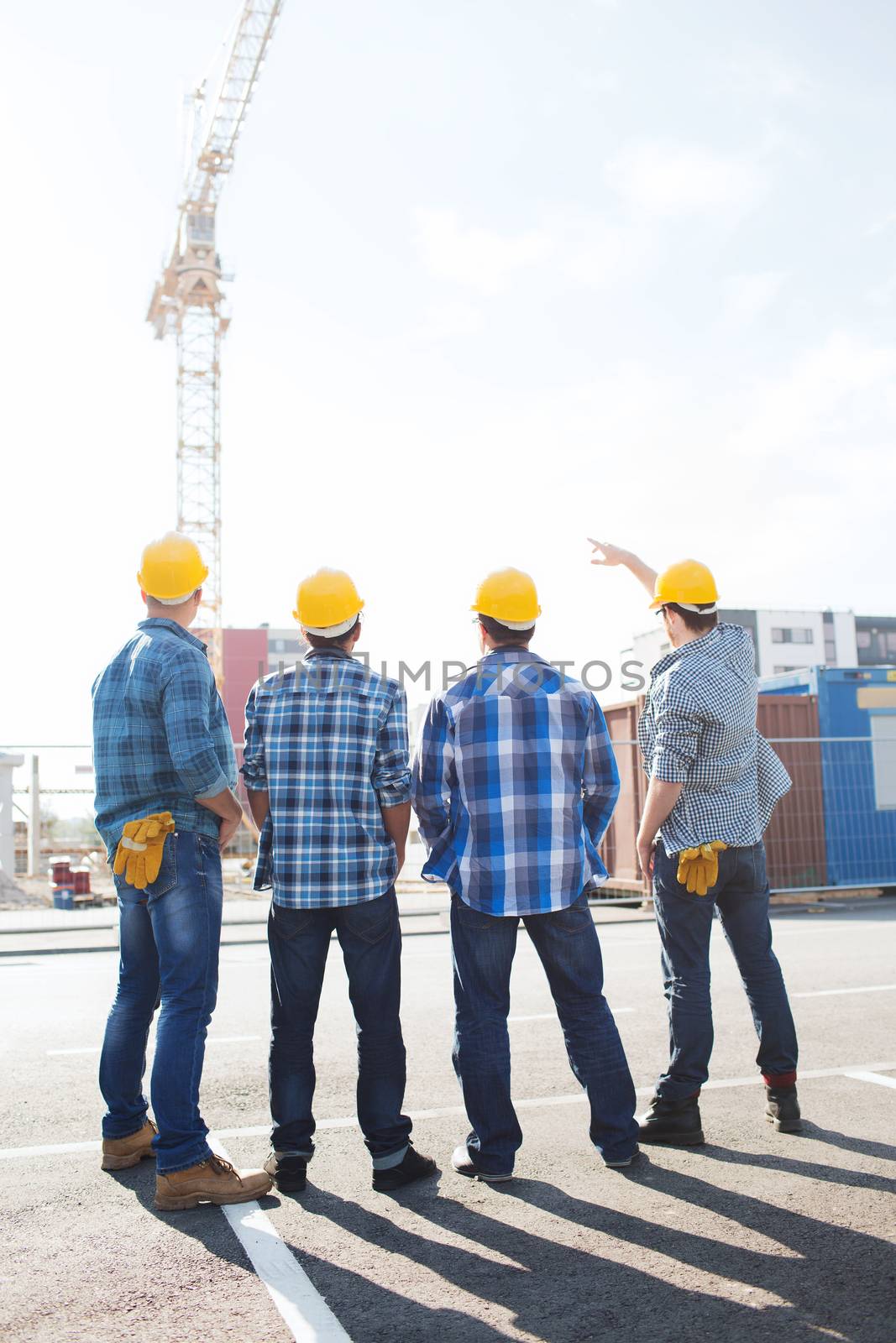 business, building, teamwork and people concept - group of builders in hardhats outdoors from back