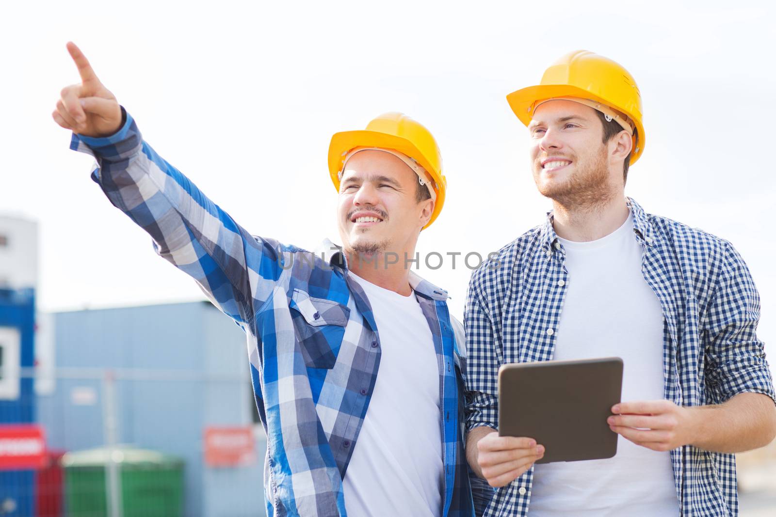 business, building, teamwork, technology and people concept - group of smiling builders in hardhats with tablet pc computer outdoors