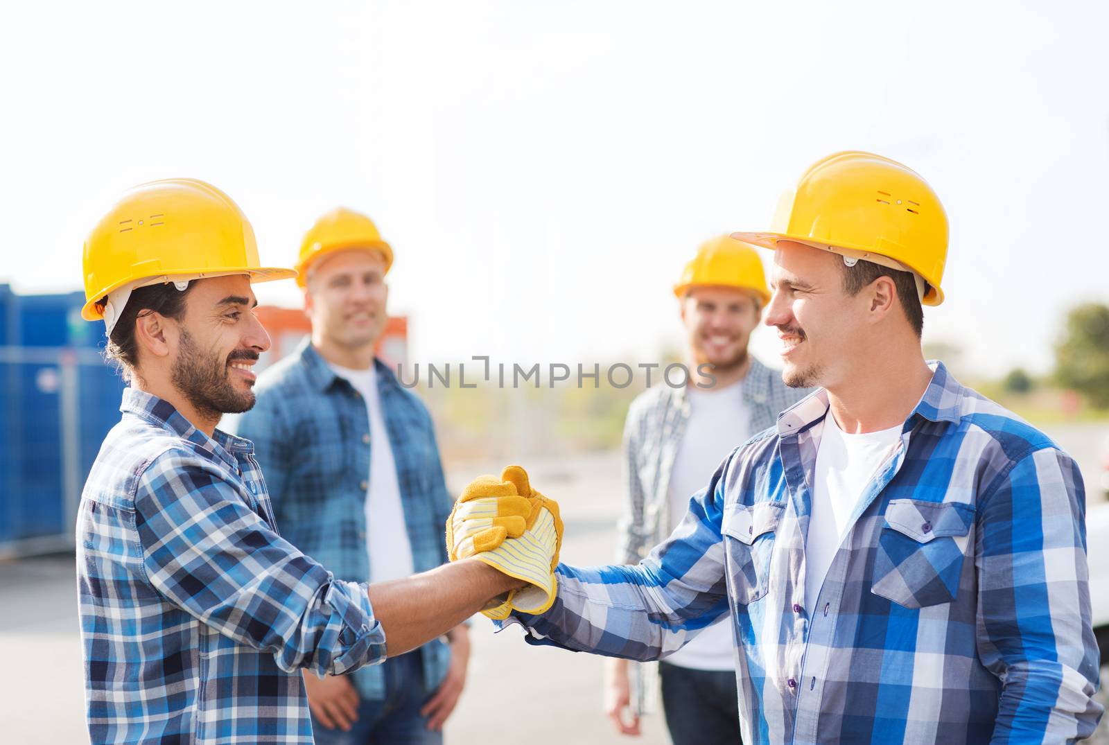 group of smiling builders shaking hands outdoors by dolgachov