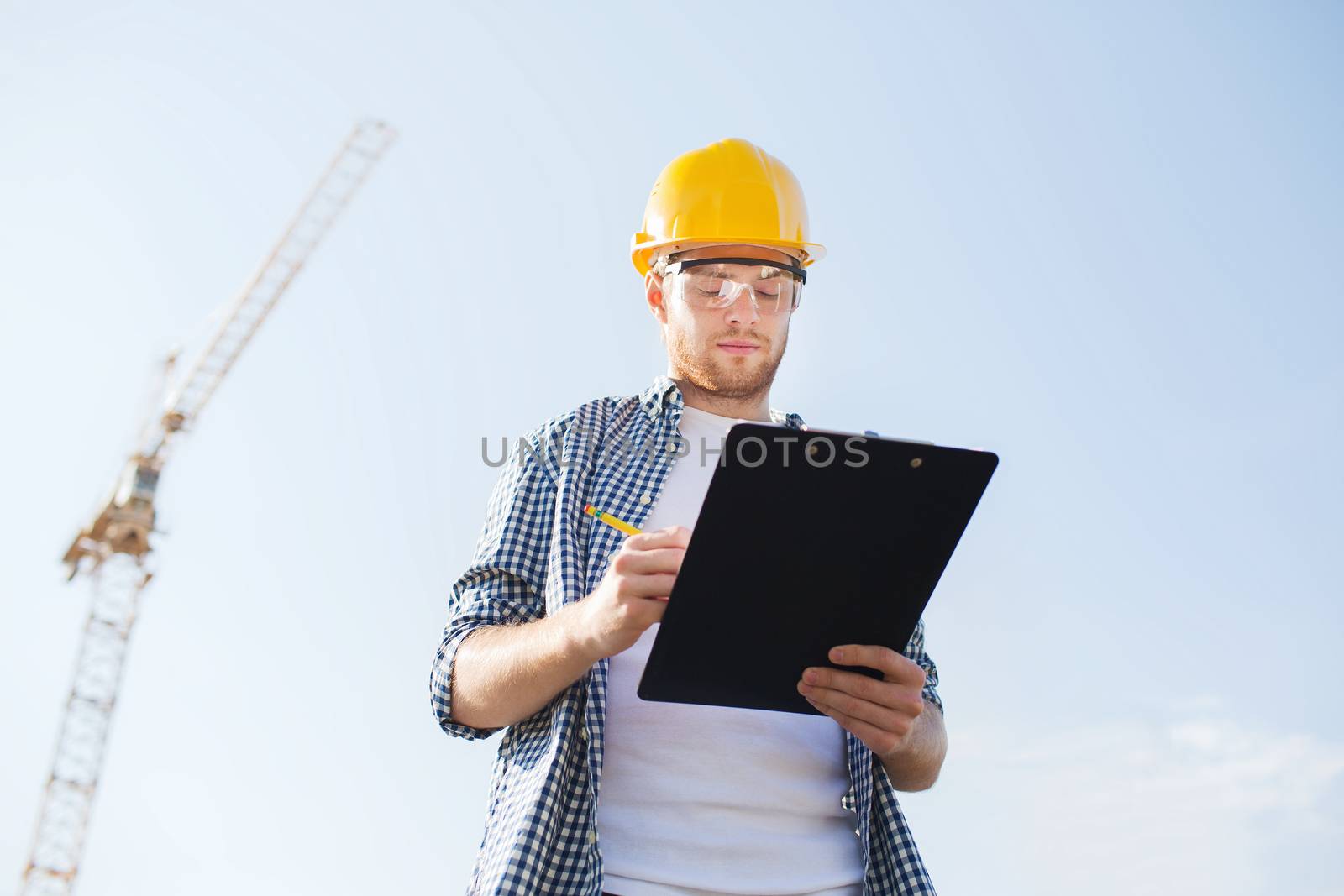 builder in hardhat with clipboard outdoors by dolgachov