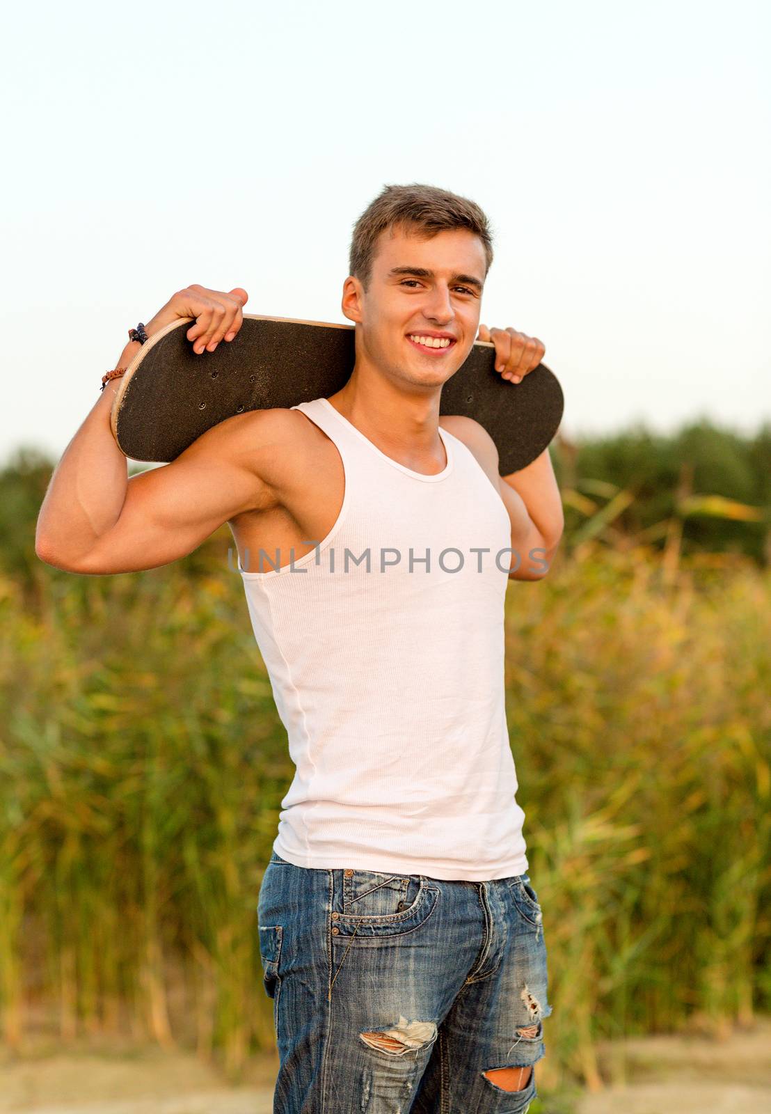 smiling teenage boy with skateboard outdoors by dolgachov