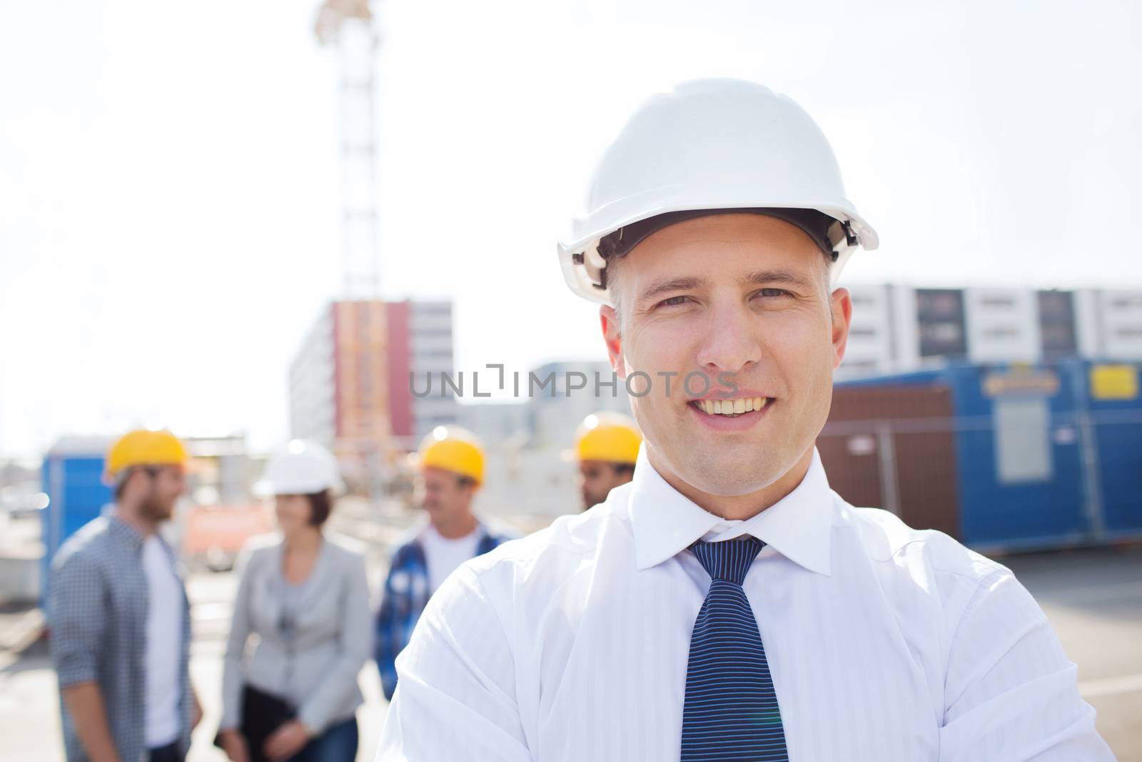 business, building, teamwork and people concept - group of smiling builders in hardhats outdoors