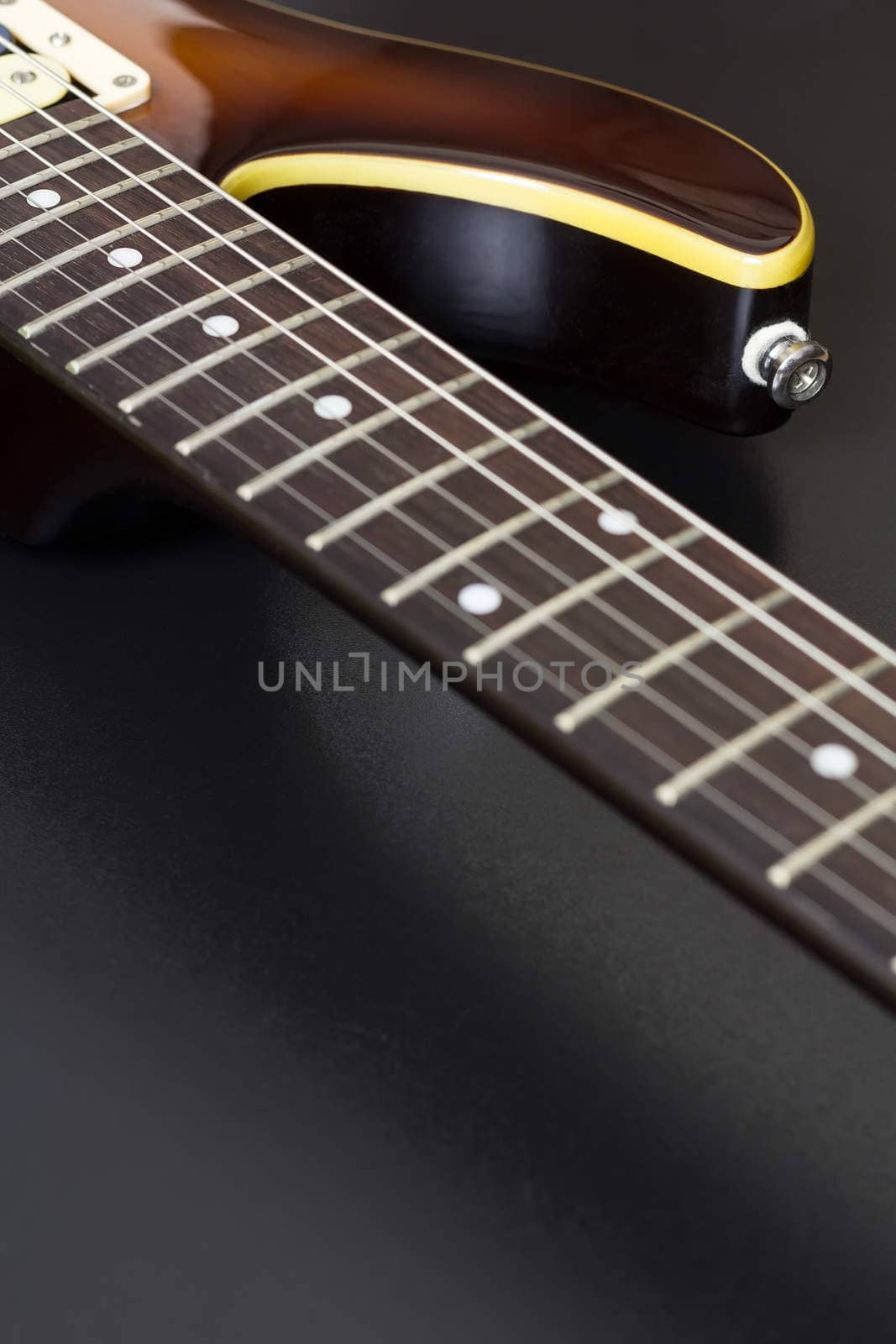 Closeup of a sunburst electric guitar with shallow depth of field on black and with copy space