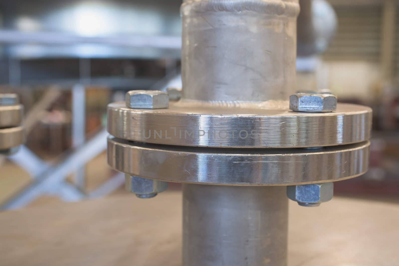 Stainless steel flange. Very shallow depth of field with only the nearest part of the flange in focus with detailed horisontal lines from the lathe visible.