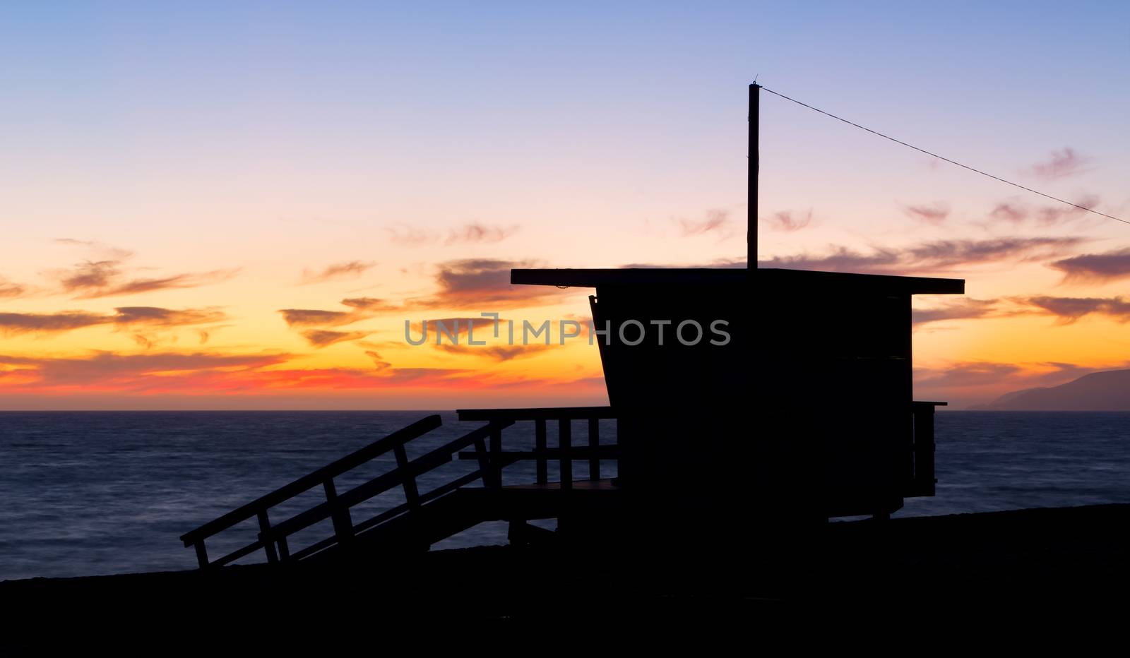 Lifeguard stand at dusk in silhouette at Zuma Beach in Malibu, California.