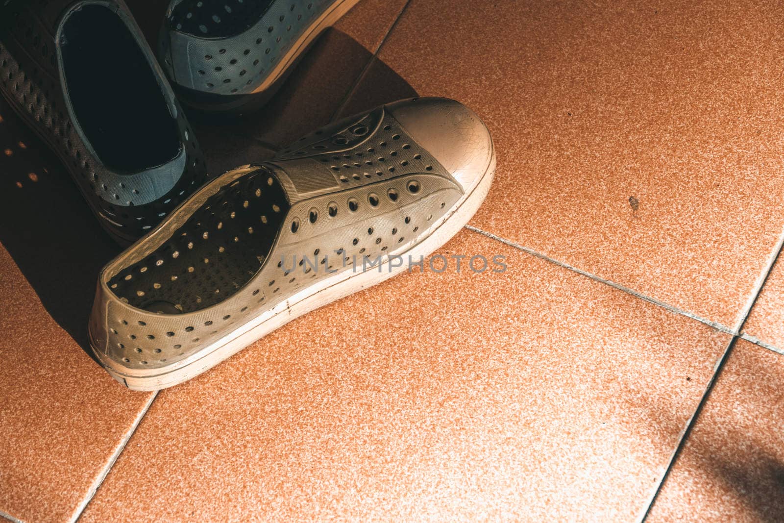 Plastic shoes on tile background with copy space, abstract background