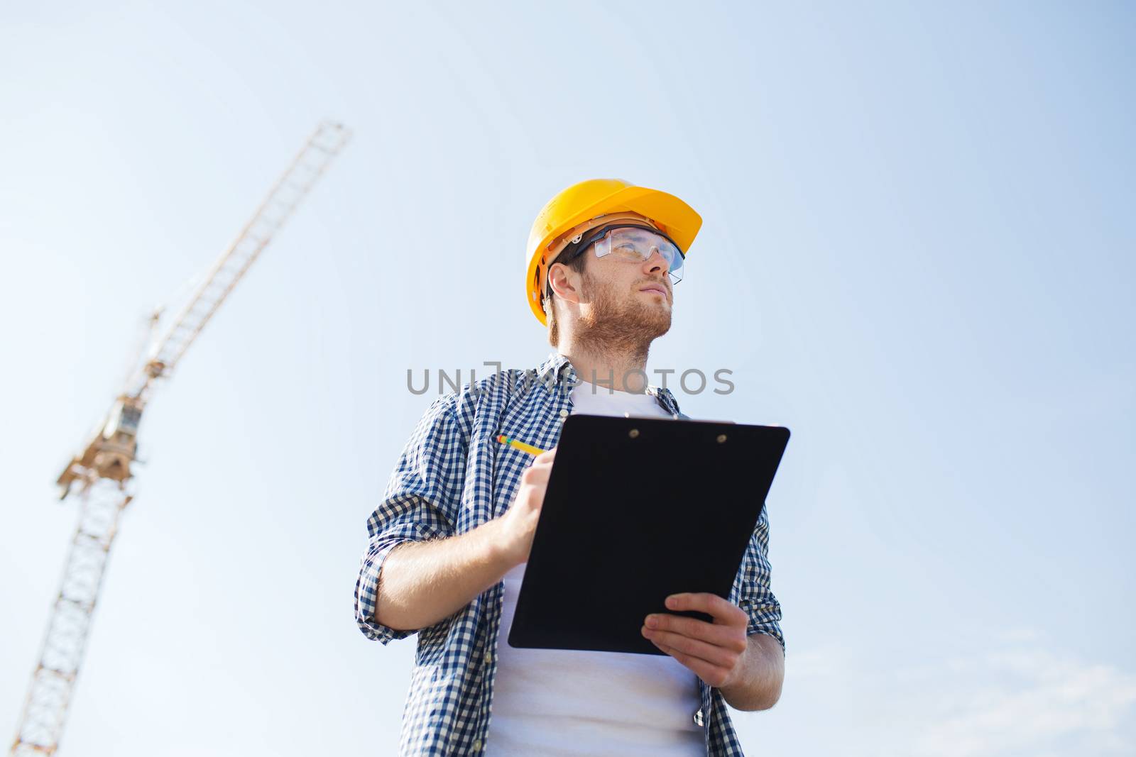 builder in hardhat with clipboard outdoors by dolgachov