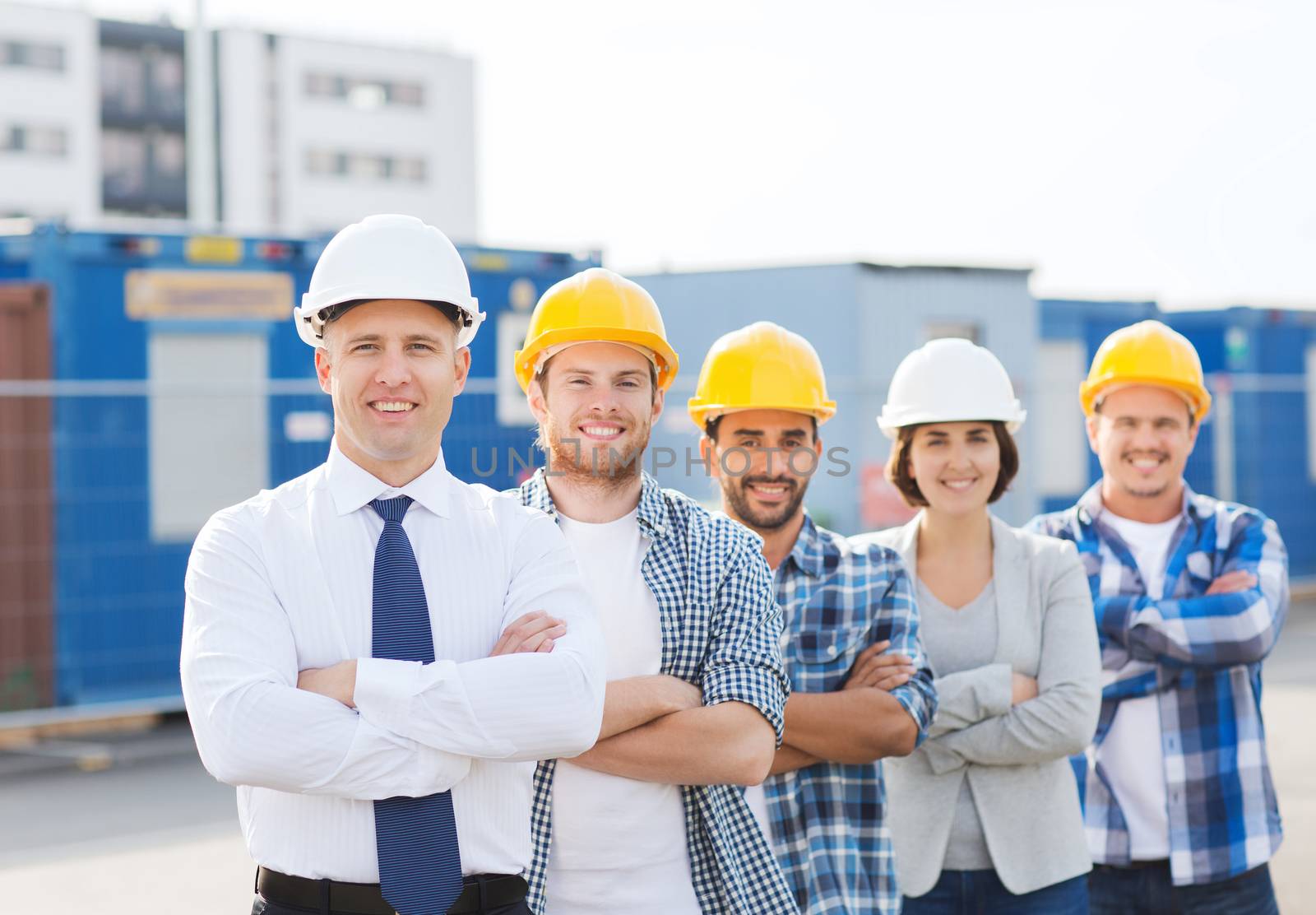 group of smiling builders in hardhats outdoors by dolgachov