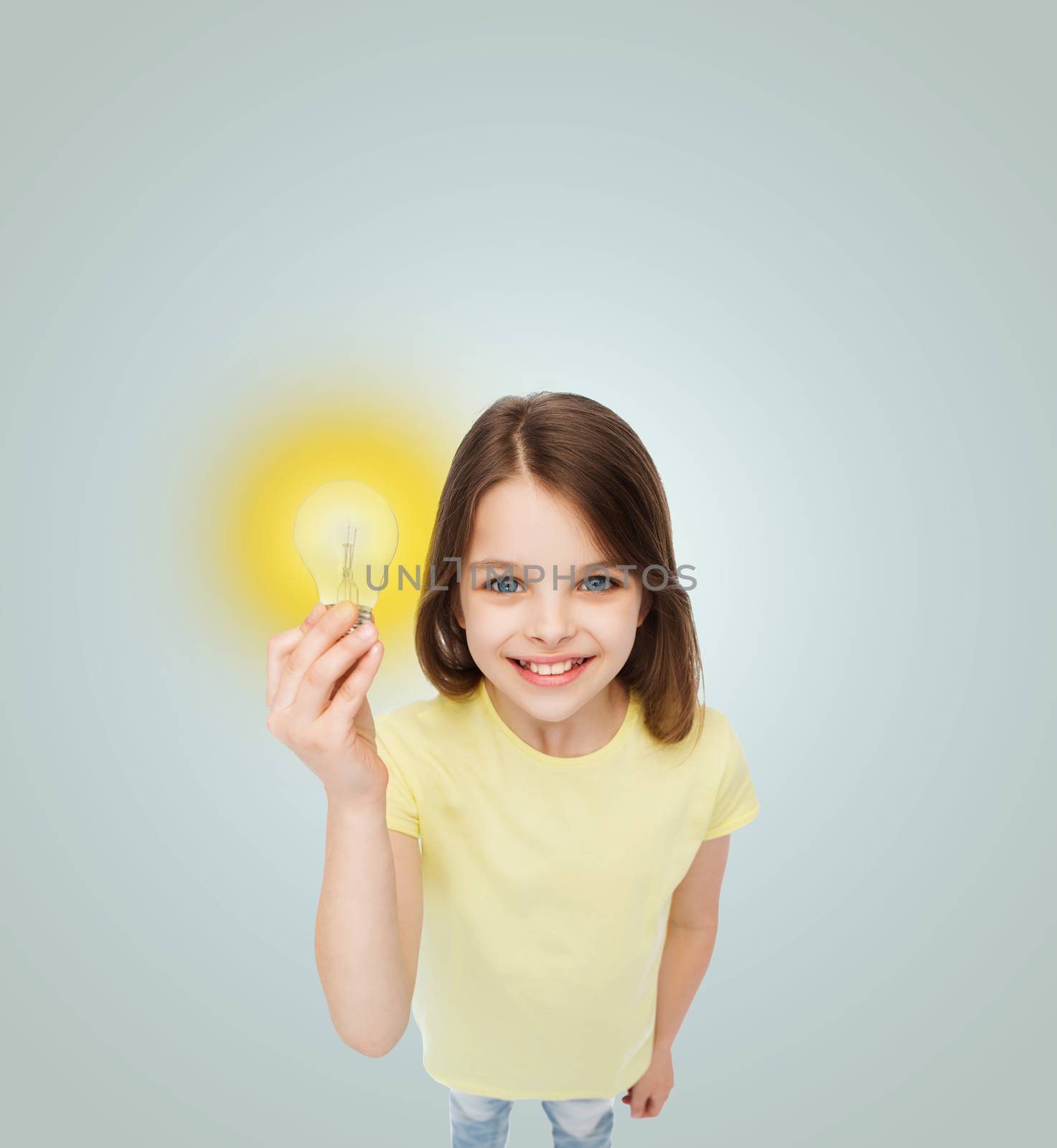 electricity, education and people concept - smiling little girl holding light bulb