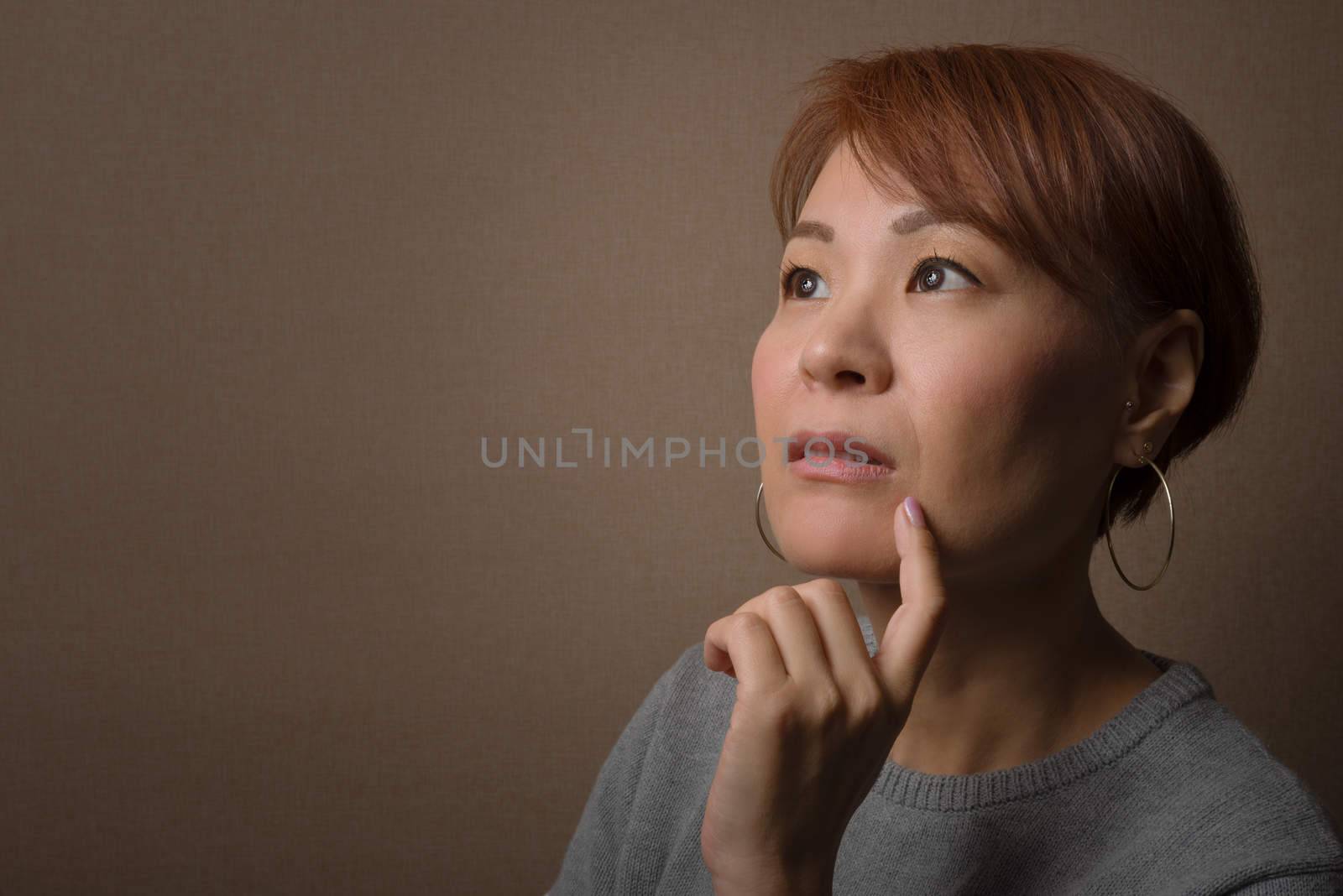 A headshot of a thoughtful middle aged Japanese woman.