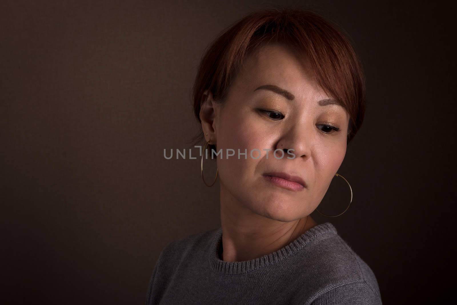A headshot of a sad looking middle aged Japanese woman.