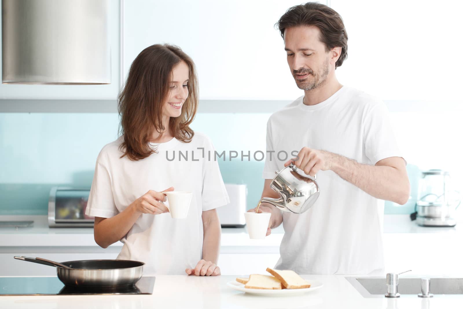 Happy couple cooking breakfast together in the kitchen