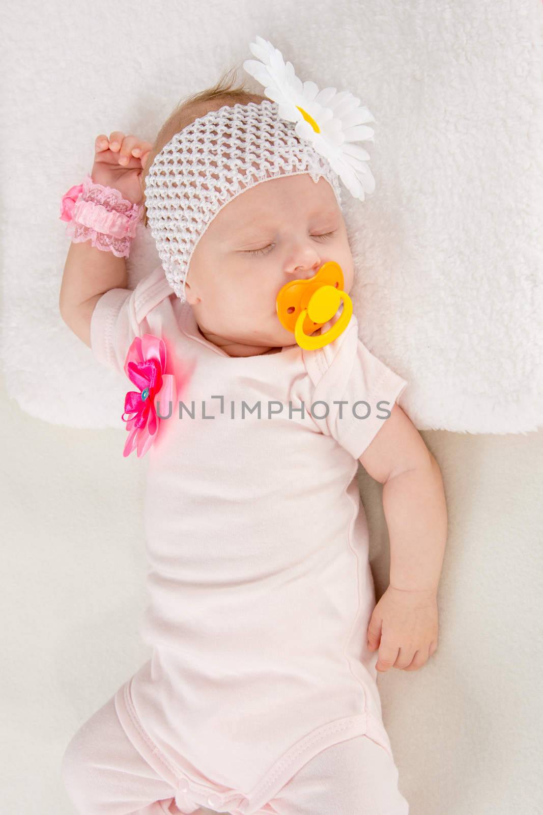 a two-month baby girl Europeans on the back with a bandage on his head with a flower lying on a soft bed