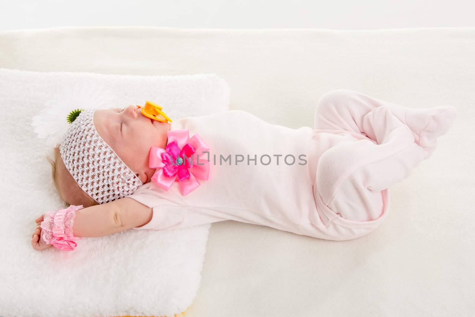 a two-month baby girl Europeans on the back with a bandage on his head with a flower lying on a soft bed