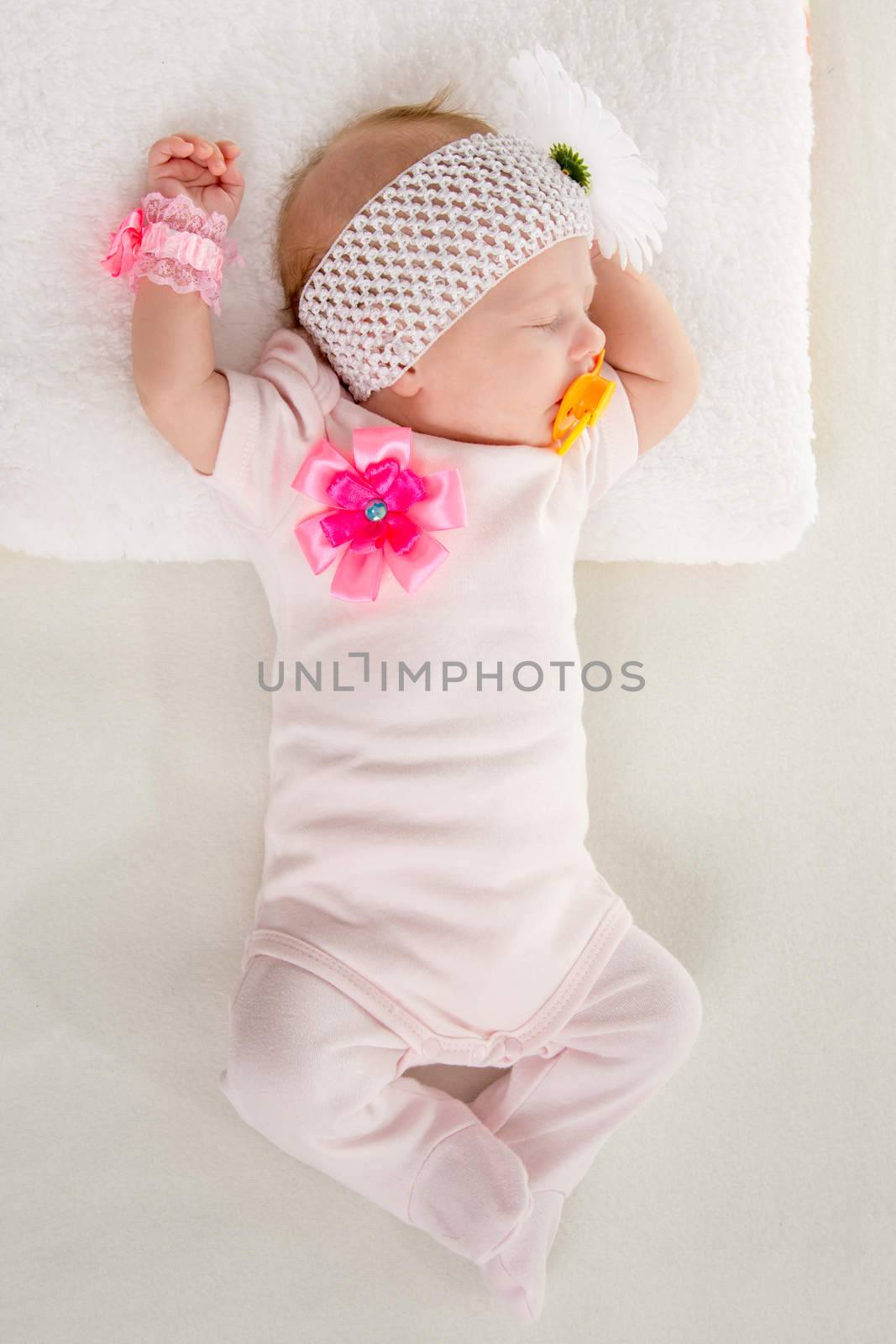a two-month baby girl Europeans lies on his back with a bandage on his head with a flower