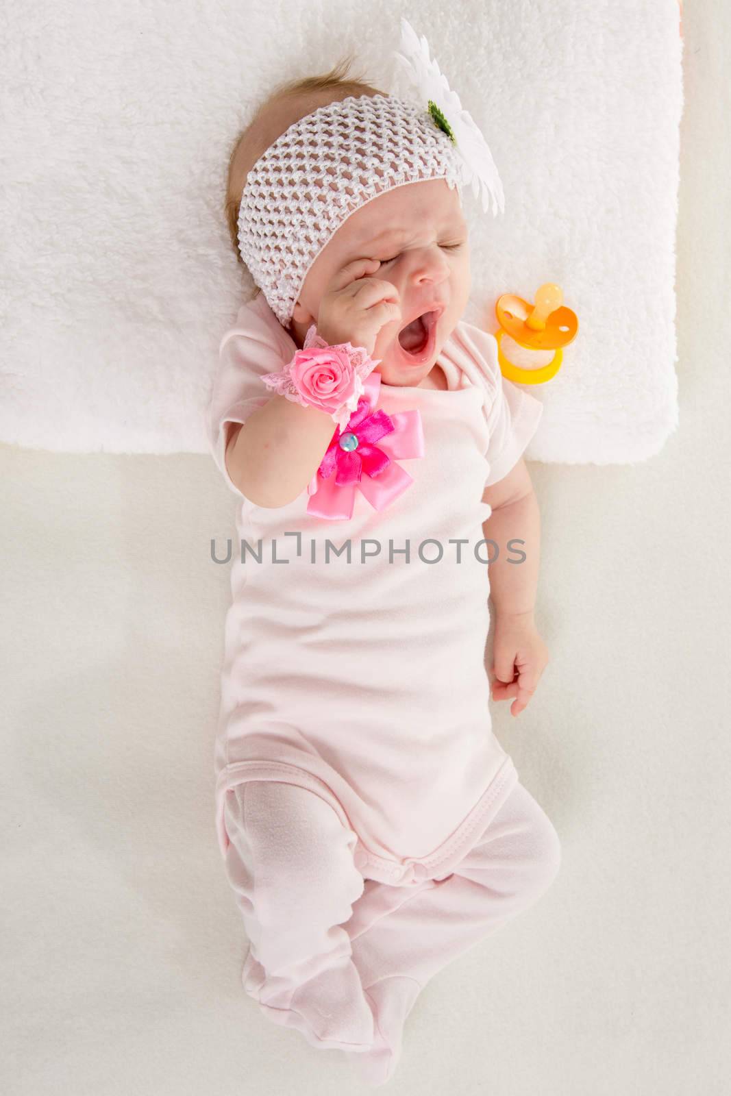 a two-month baby girl Europeans lies on his back with a bandage on his head with a flower