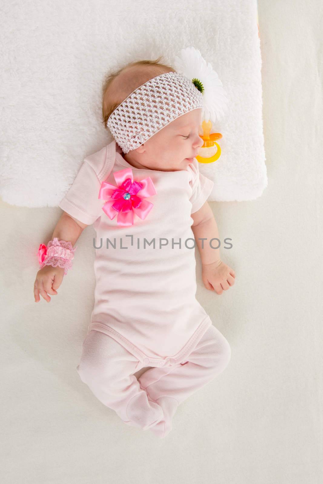 a two-month baby girl Europeans lies on his back with a bandage on his head with a flower