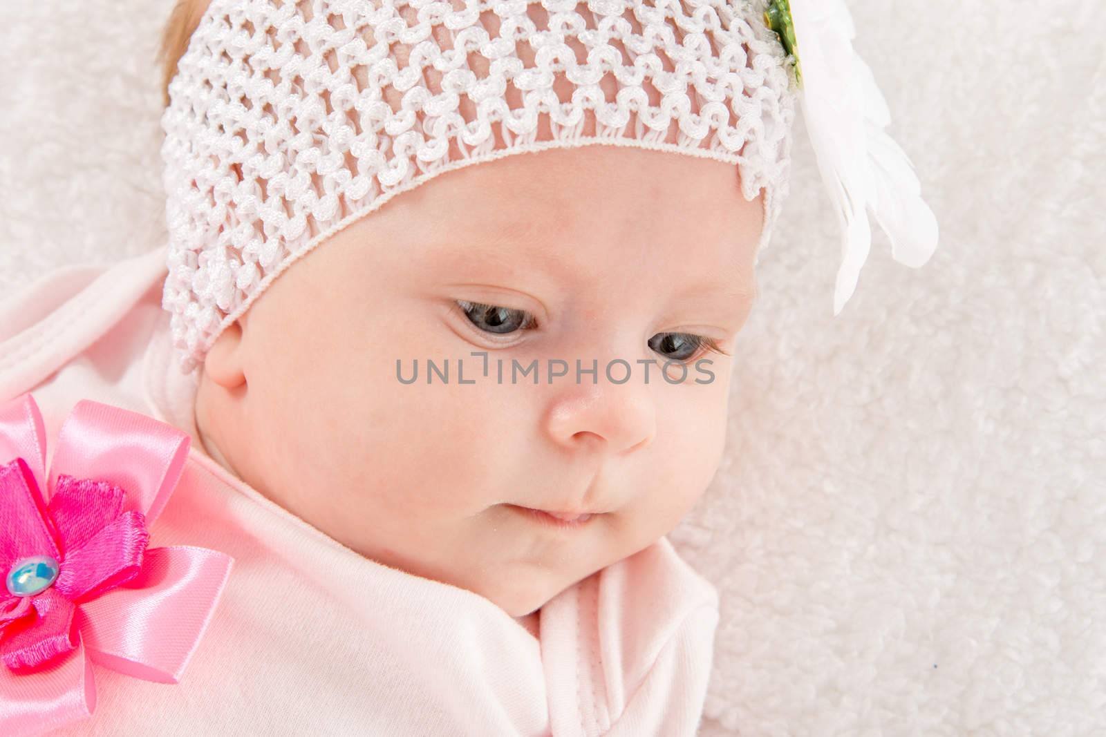 a two-month baby girl Europeans on the back with a bandage on his head with a flower lying on a soft bed