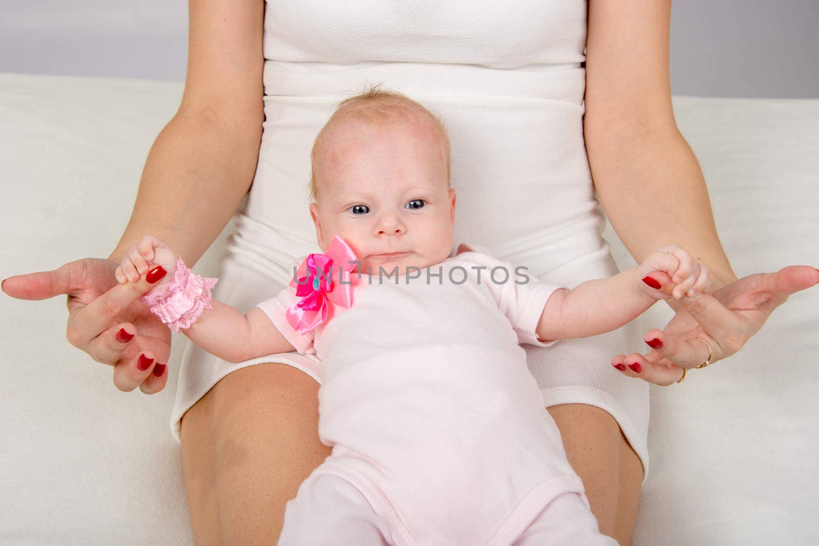 a two-month baby lying on her back on her mother's lap and looking at her