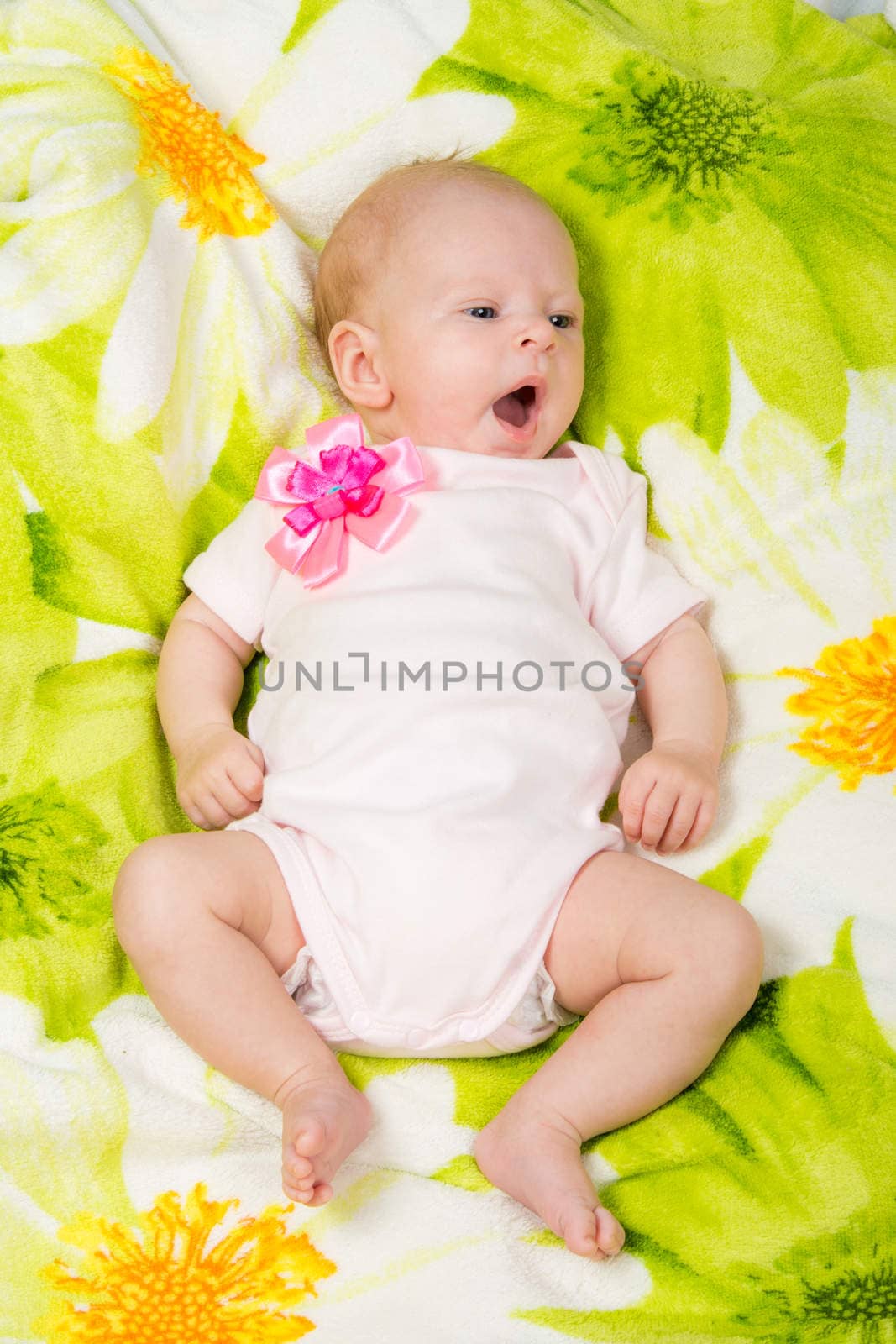 a two-month baby girl lying on the bed Europeans on colored coverlet