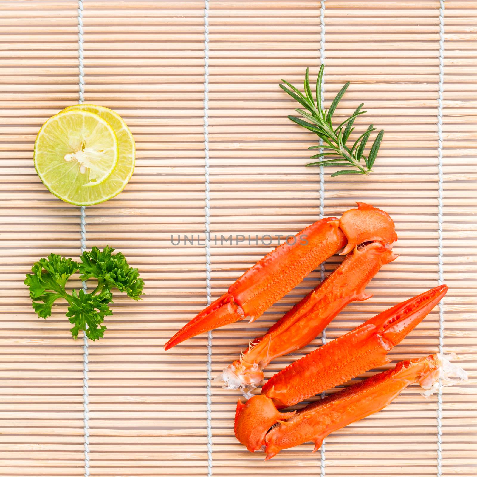 Boiled crab claws with lime and parsley on bamboo background.