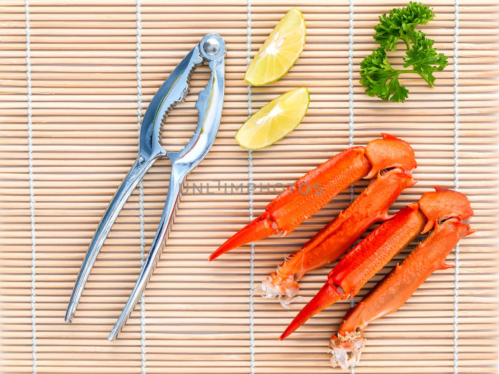 Boiled crab claws with lime and parsley on bamboo background.