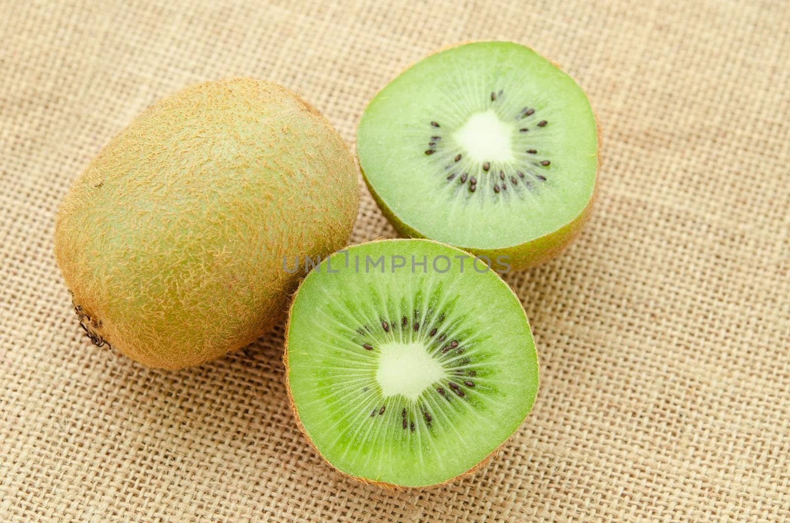 Fresh kiwi fruit and slic fruit put on sack background.