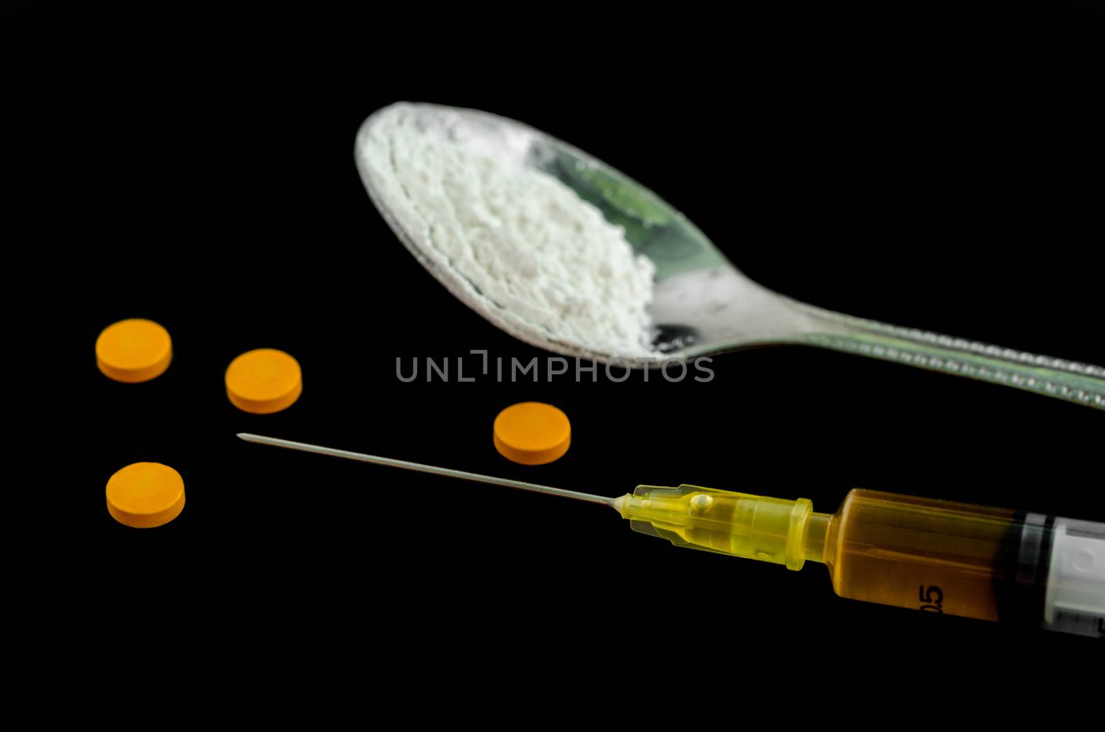 Cocaine, amphetamine, spoon and focus at the disposable syringe on a black background. Narcotics addiction.