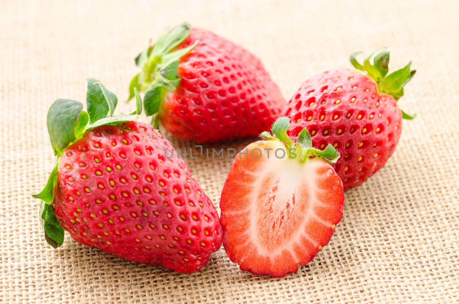 Strawberries with leaves on sacking background