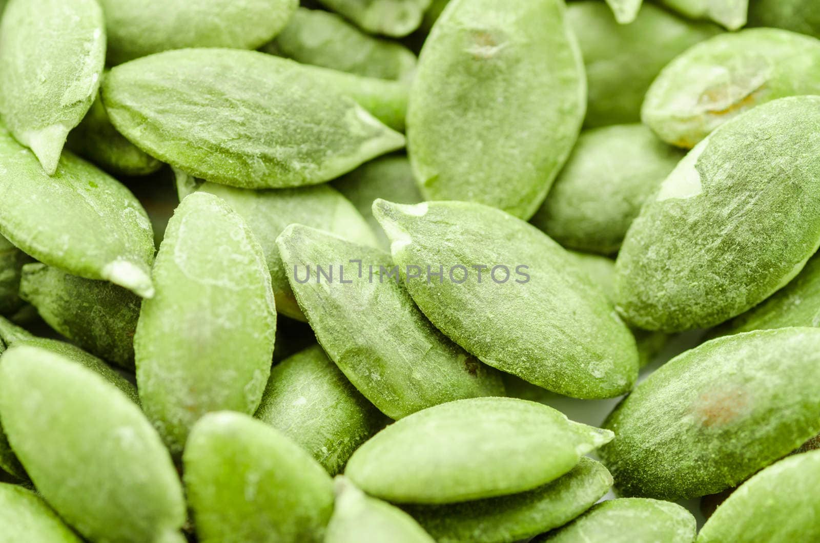 Macro background texture of dried green pumpkin seeds.