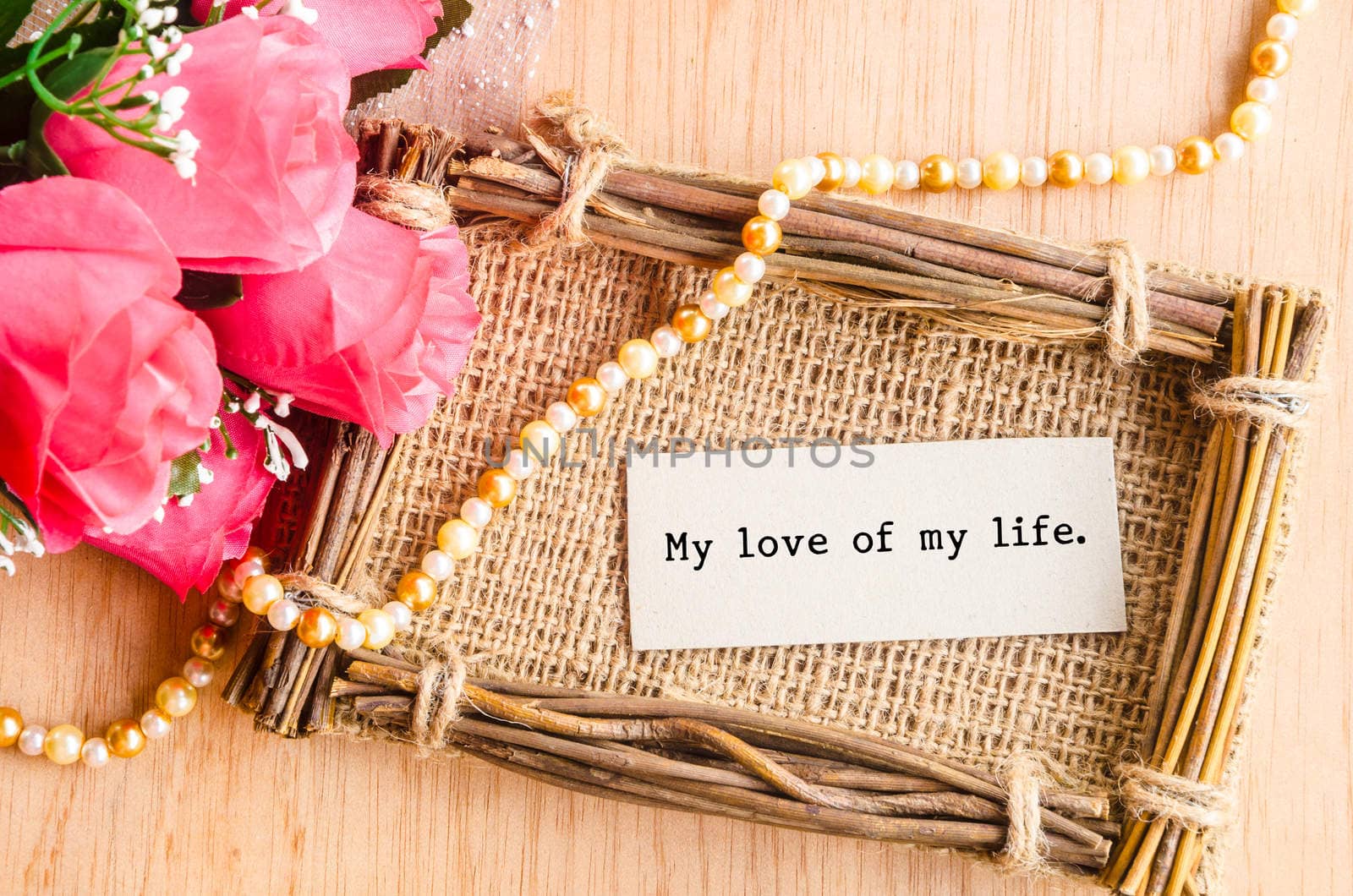 My love of my life on paper tag with pink rose on wooden background.