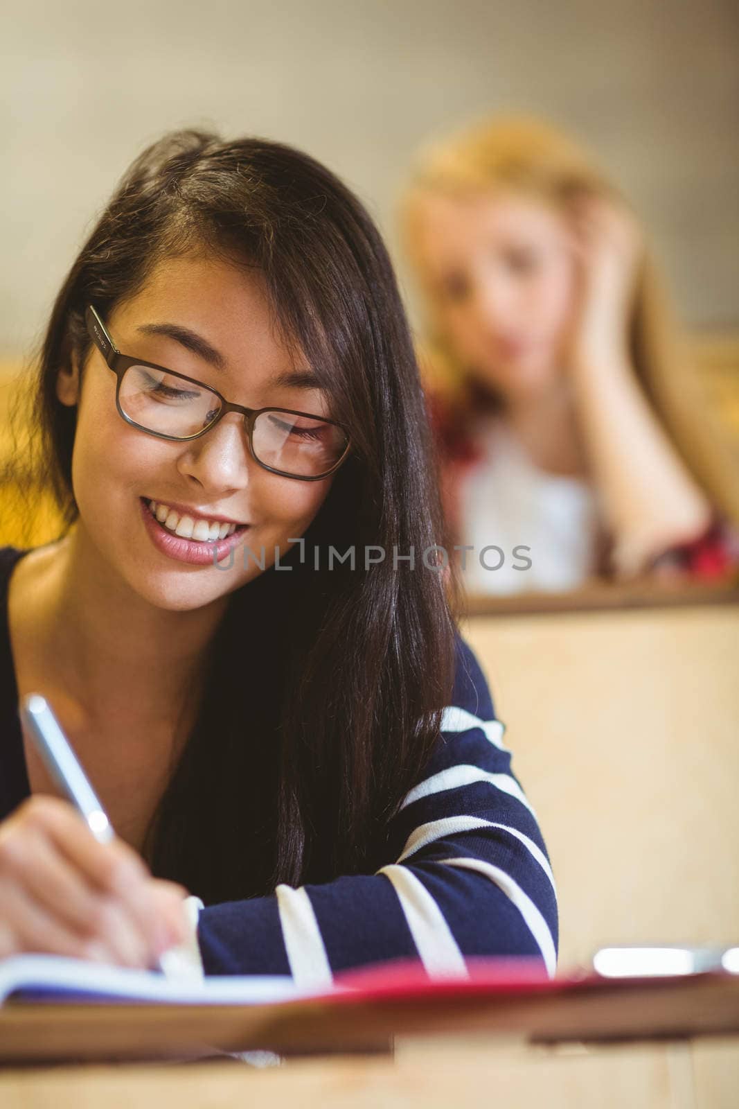 Smiling student writing on notebook by Wavebreakmedia