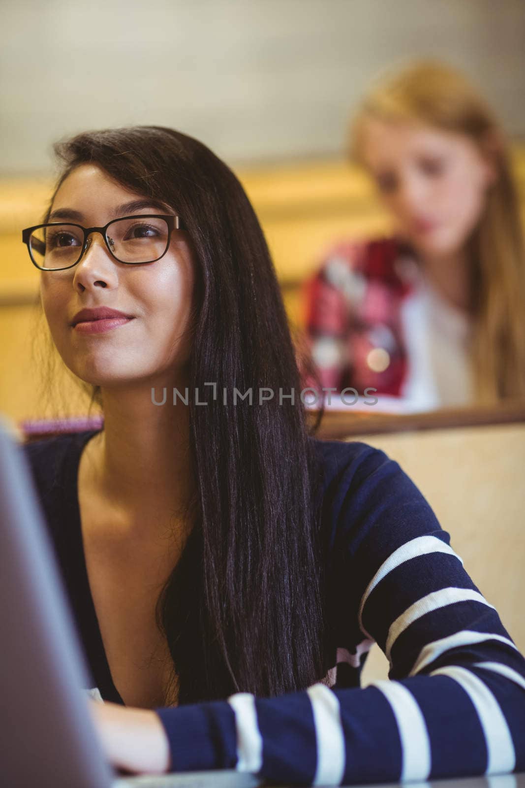 Smiling student using laptop during class by Wavebreakmedia