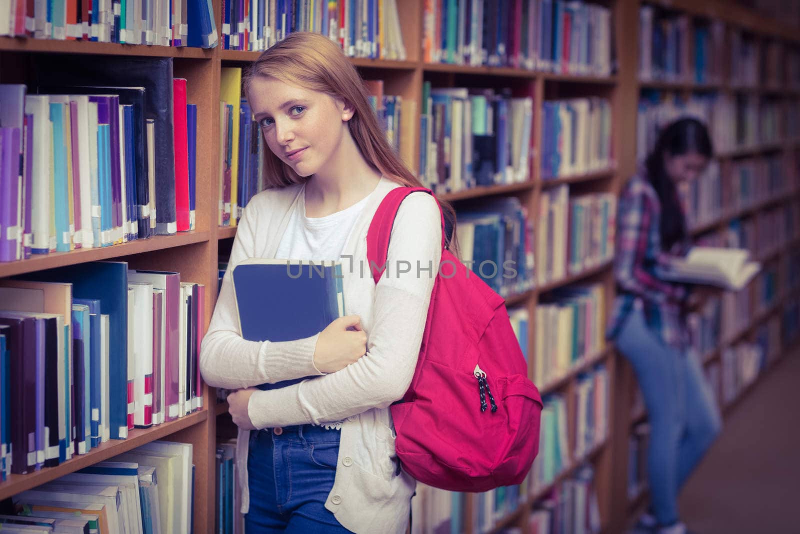 Smiling student leaning against bookshelves at the university