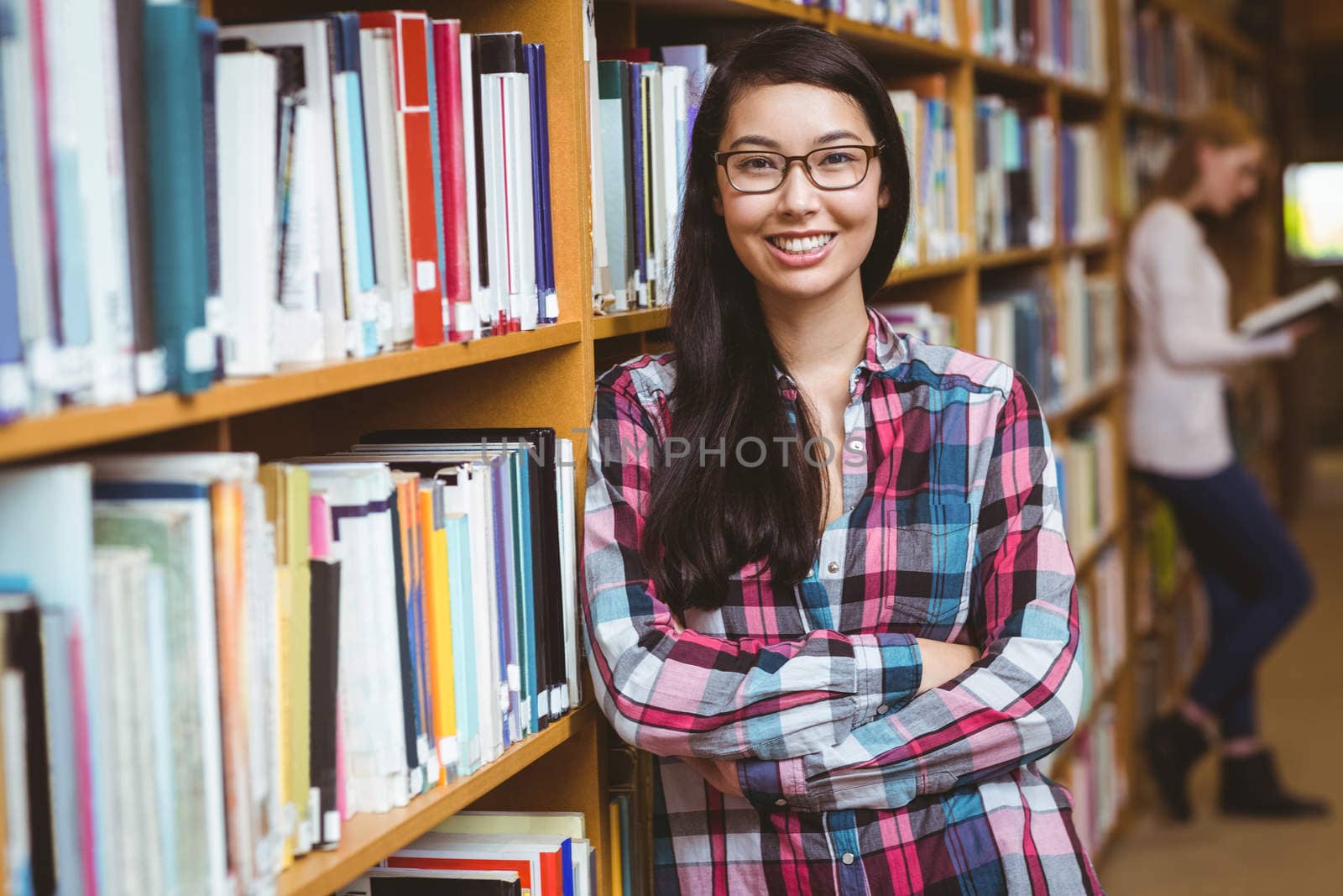 Smiling student leaning against bookshelves at the university
