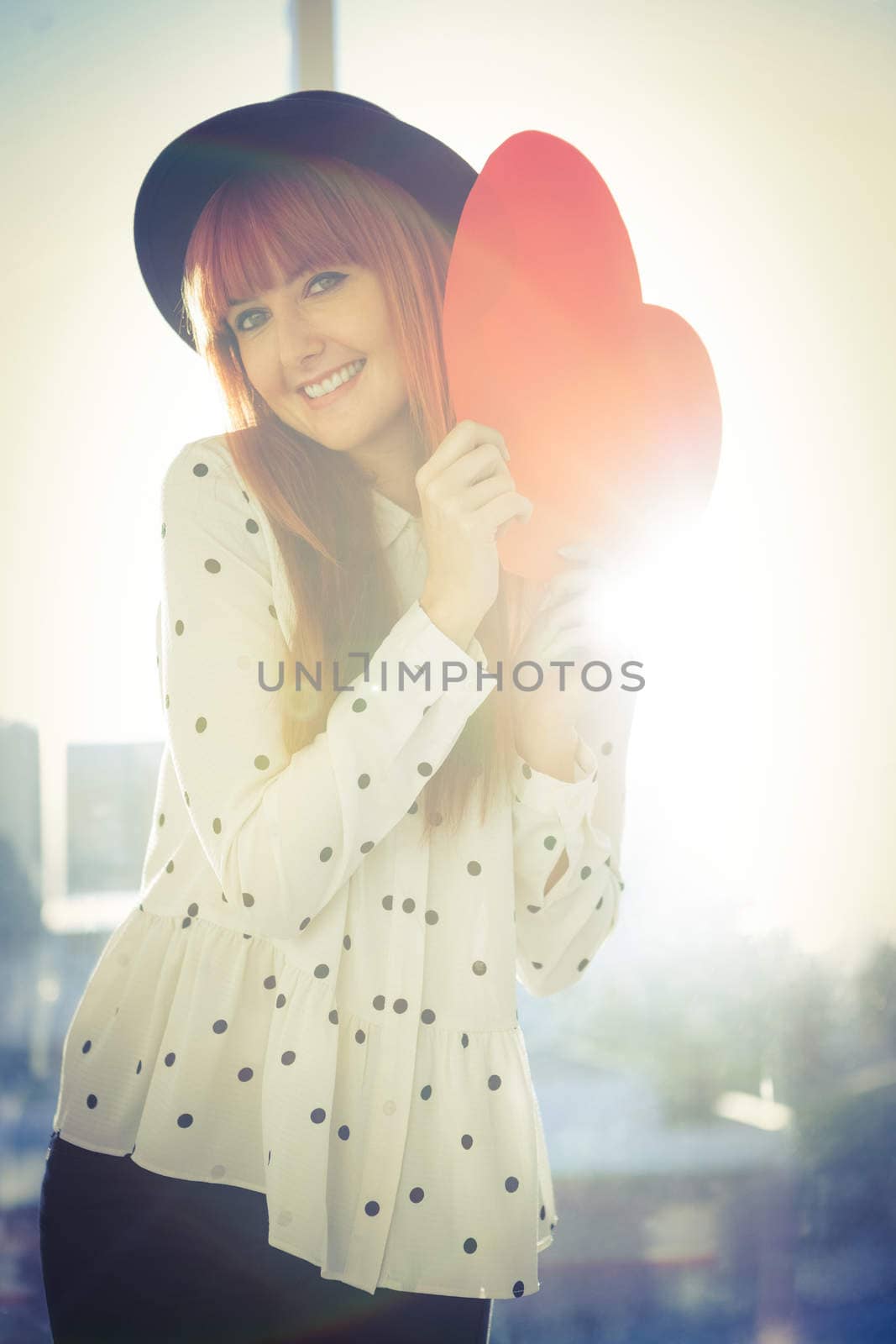 Attractive hipster woman behind a red heart in a bright room