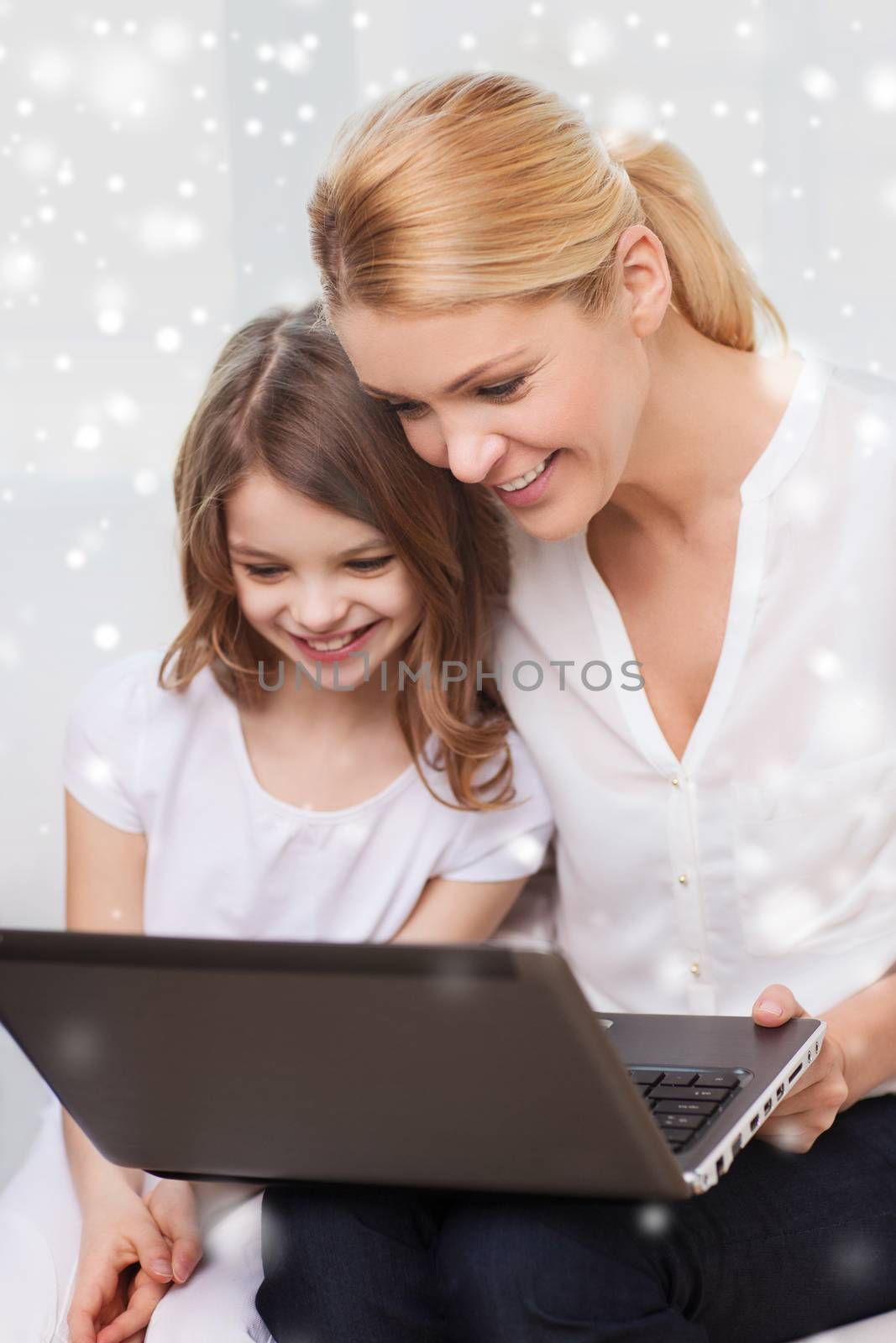 family, child, technology and home concept - smiling mother and little girl with laptop at home