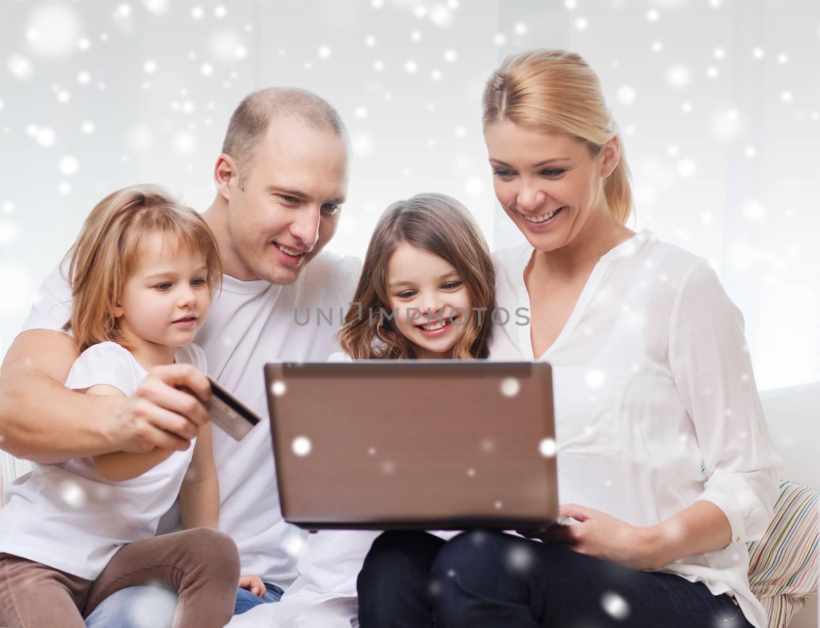 family, shopping, technology and people concept - happy family with laptop computer and credit card over snowflakes background