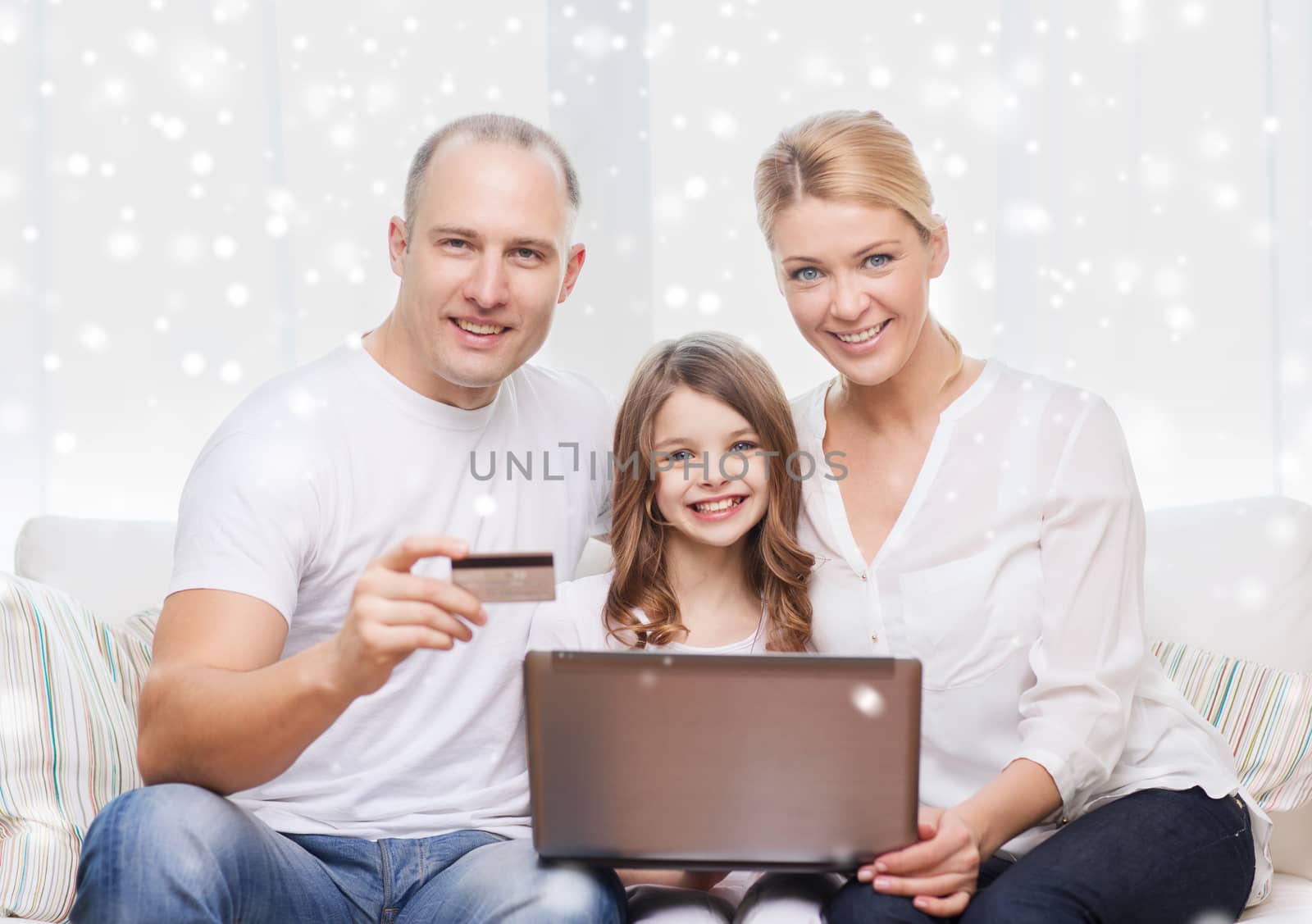 family, shopping, technology and people concept - happy family with laptop computer and credit card over snowflakes background