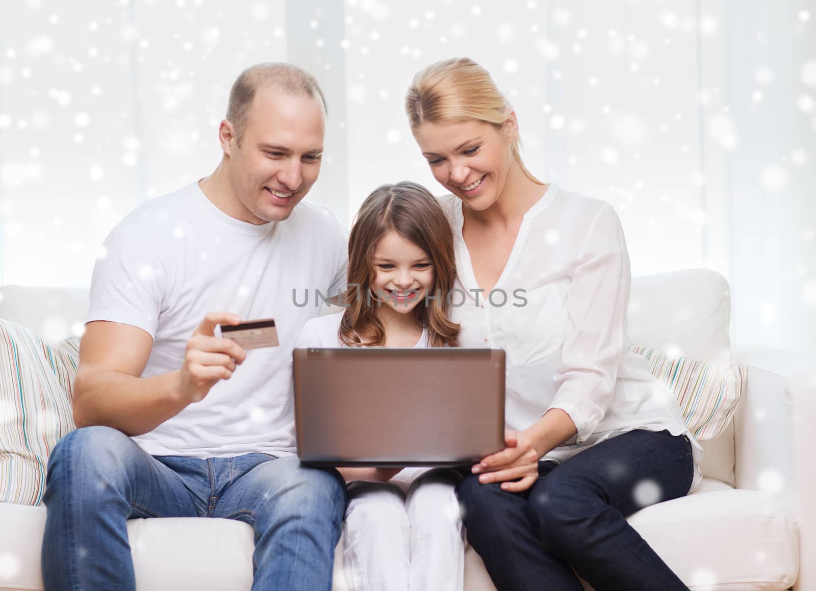 family, shopping, technology and people concept - happy family with laptop computer and credit card over snowflakes background