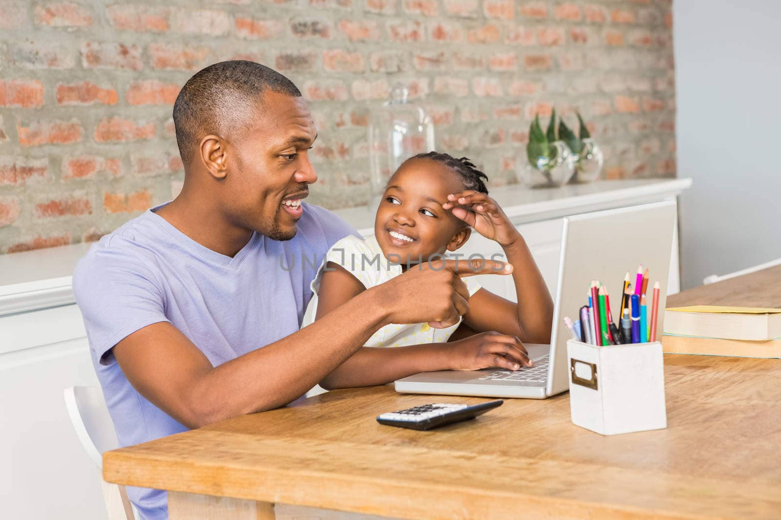 Cute daughter using laptop at desk with father by Wavebreakmedia