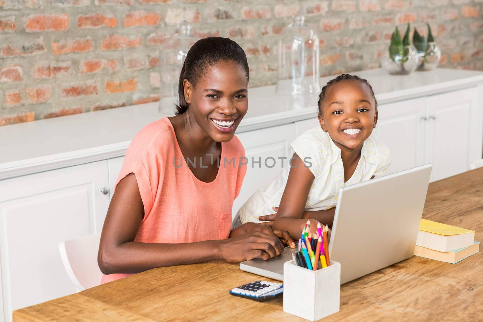 Cute daughter using laptop at desk with mother by Wavebreakmedia
